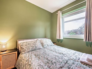 A room with a bed, a bedside lamp, and a window with curtains. - 2 Bed in Swansea (oc-90367) (Oxwich)