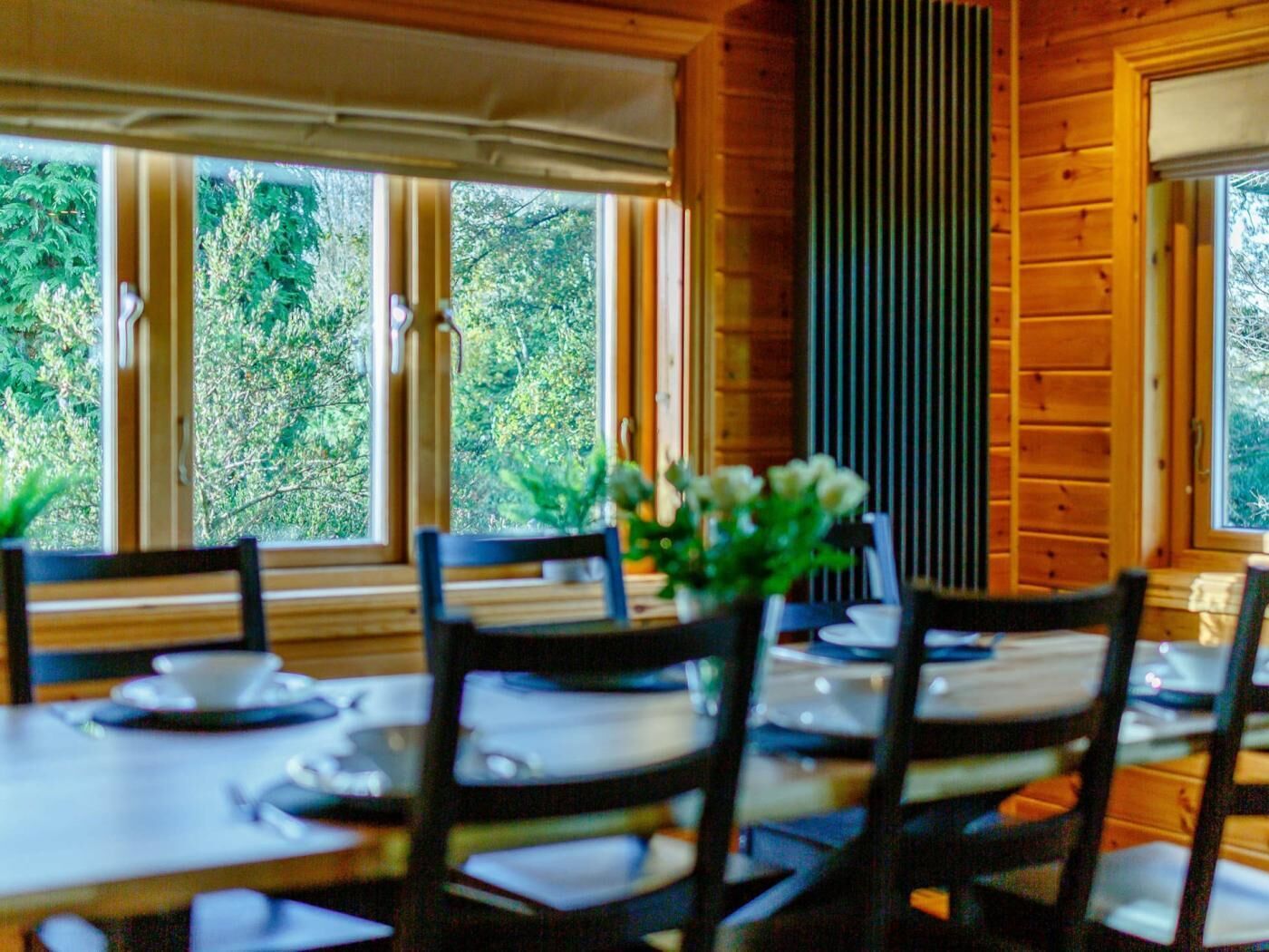 Comedor con paredes de madera, ventanas amplias y una mesa dispuesta para cuatro.