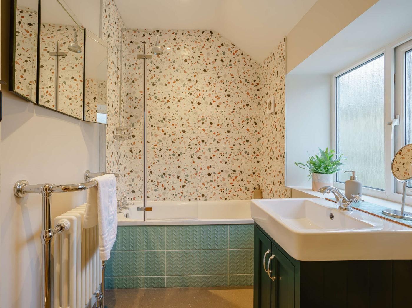 Un bagno con doccia, vasca, lavandino e finestra.