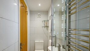 Ein modernes Badezimmer mit Toilette, Waschbecken und einer Duschkabine aus Glas.