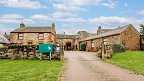 A stone building with a paved pathway leading to a door. - 2 Bed in Penrith (oc-90415) (Gamblesby)