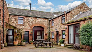A courtyard with stone buildings, a wooden bench, and potted plants. - 2 Bed in Penrith (oc-90415) (Gamblesby)