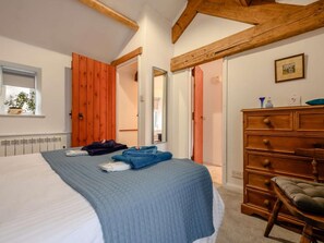 Ein Schlafzimmer mit einem Bett, einem Holzschrank und einem Fenster mit einer Pflanze.