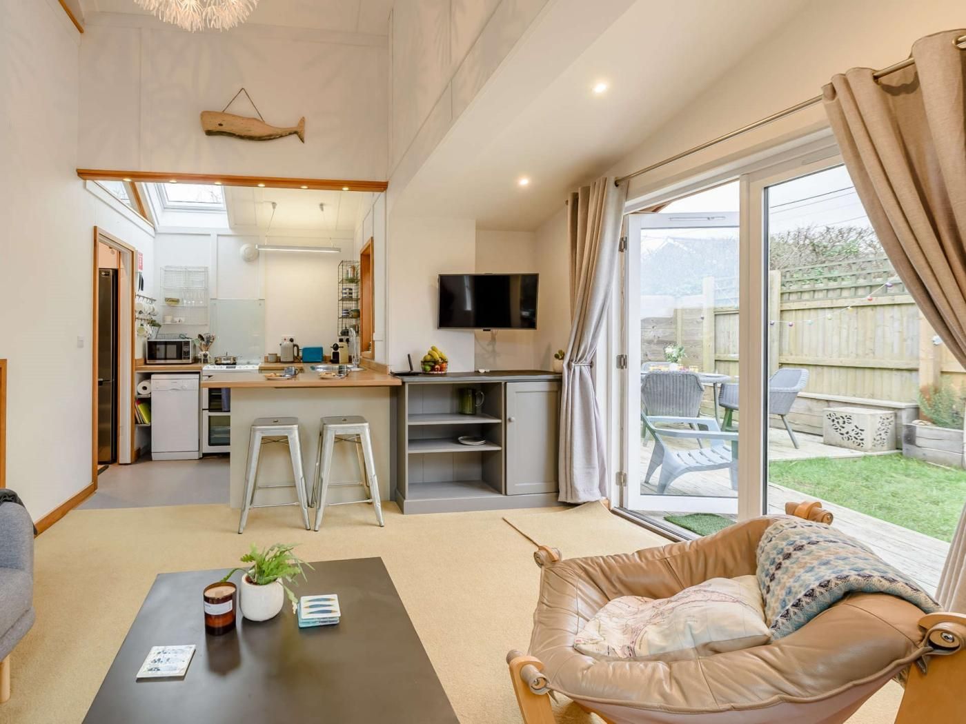 Een ruimtelijk ingerichte leefruimte met een kitchenette, een eethoek en een zithoek met uitzicht op de achtertuin.