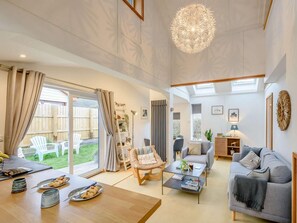 A spacious living area with a dining table, sofas, and a large chandelier. - 3 Bed in Braunton (oc-90437) (Croyde)