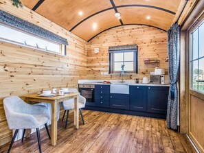 A cozy wooden cabin interior with a dining area, kitchen, and large windows. - 1 Bed in Rhayader (oc-90285) (Saint Harmon)