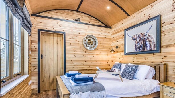 Ein Holzblockhaus-Interieur mit Bett, Nachttisch und Fenster.