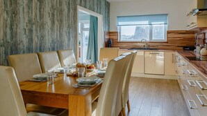 Eine moderne Küche mit Fenster, Holzvertäfelung und einer Essecke mit Tisch für vier Personen.