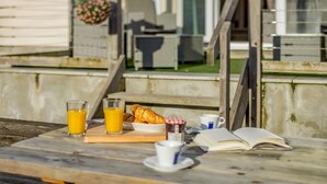 Ein Frühstücksarrangement mit Croissants, Orangensaft und einem Buch auf einem Tisch.