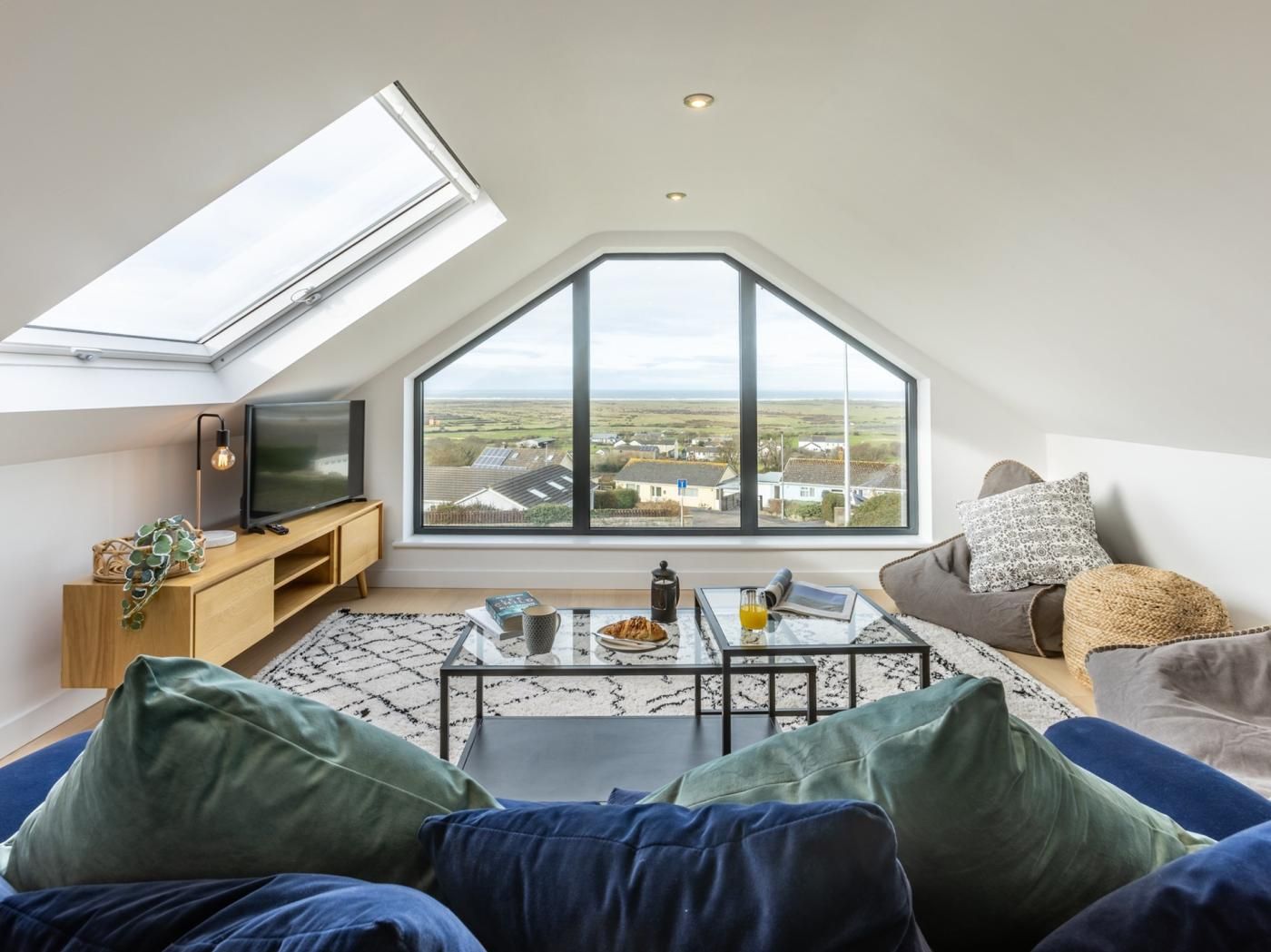 Une chambre de style loft moderne, dotée d’une lucarne, d’une grande fenêtre offrant une belle vue, d’un téléviseur et d’un coin salon confortable.