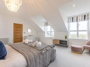 Ein Schlafzimmer mit einem Bett, einem Schminktisch, einem Frisiertisch, einem runden Spiegel, einem Fenster mit Blick und einer Hängelampe.
