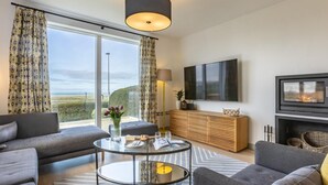 Una sala de estar moderna con un sofá, una mesa de centro de vidrio, un televisor y una chimenea.