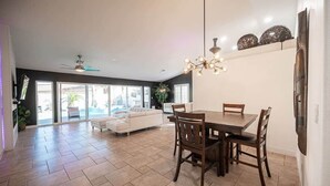 Un vaste espace de vie comprenant une table à manger, des chaises, un canapé et un ventilateur de plafond.