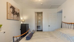 Ein Schlafzimmer mit einem Bett, einem Schreibtisch, einem Stuhl, einer Lampe und einem Bild an der Wand.