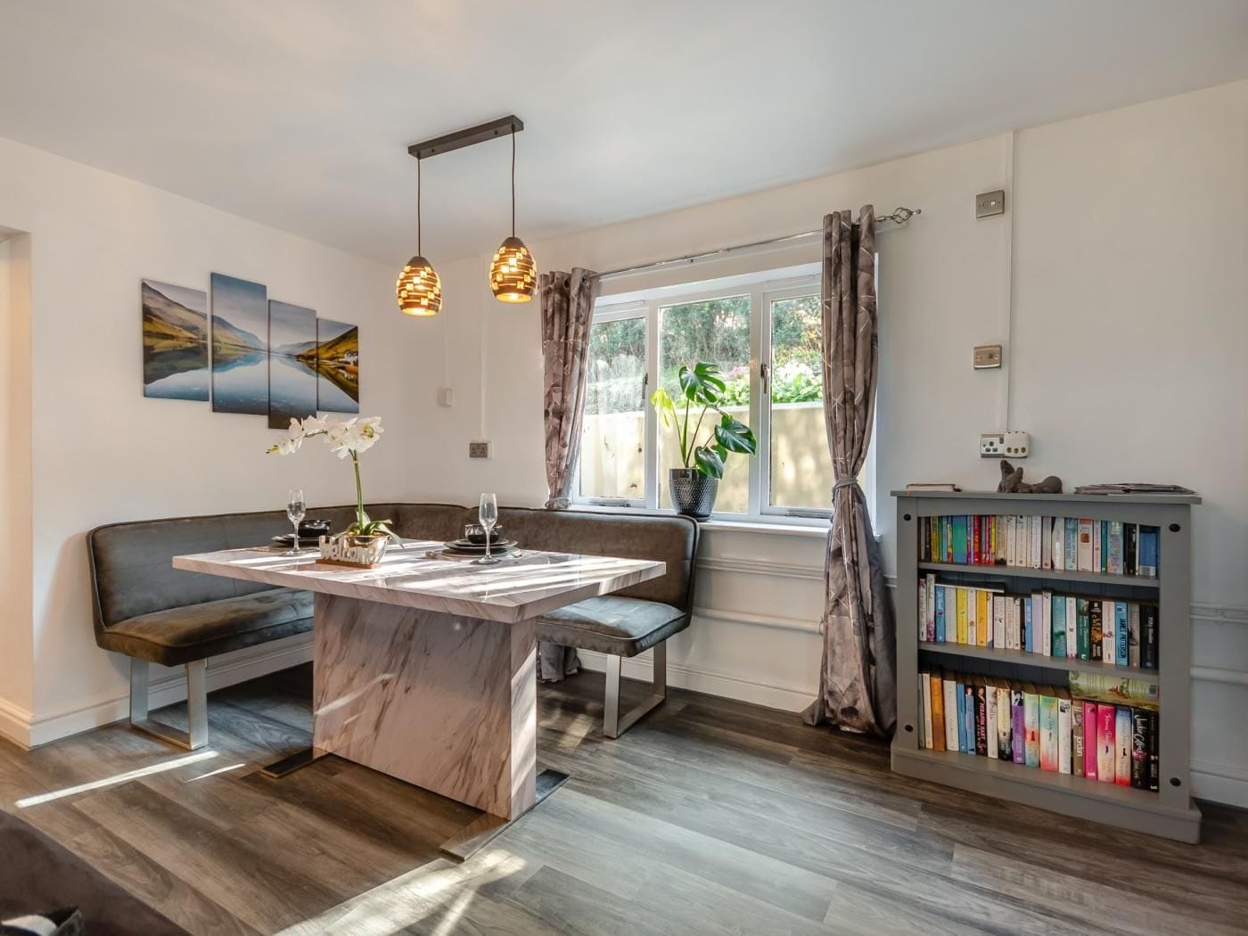 Une cuisine moderne dotée d’un îlot en marbre, de luminaires suspendus, d’une banquette intégrée et d’une bibliothèque.