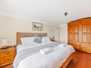 A bedroom with a bed, bedside table, lamp, and a wooden wardrobe. - 3 Bed in Corwen (oc-90459) (Corwen)