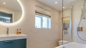 A modern bathroom with a freestanding bathtub, a round mirror, and a window with a view. - 3 Bed in Belford (oc-90351) (Belford)