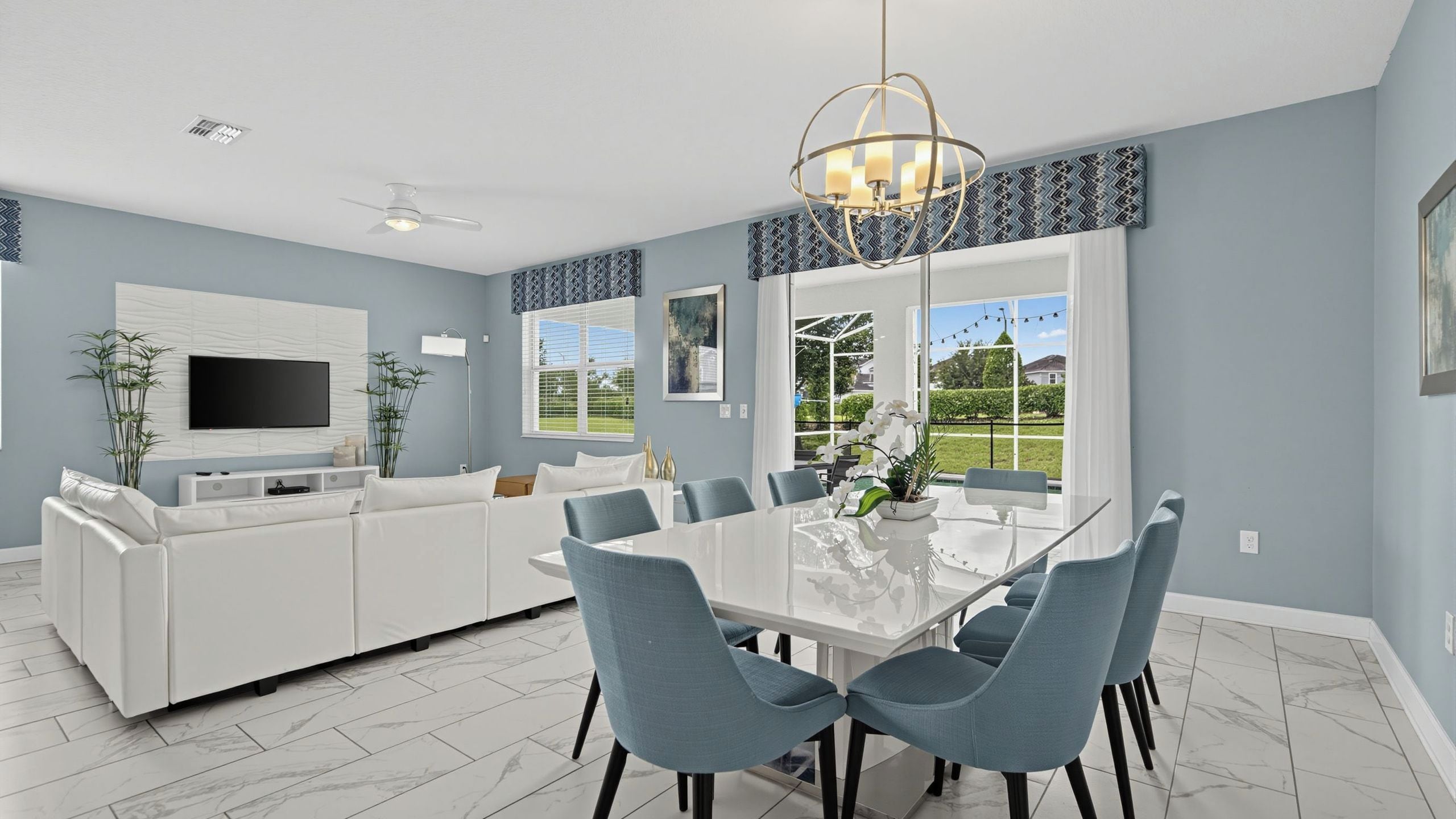 A modern kitchen with a dining area, white cabinetry, and a large window.