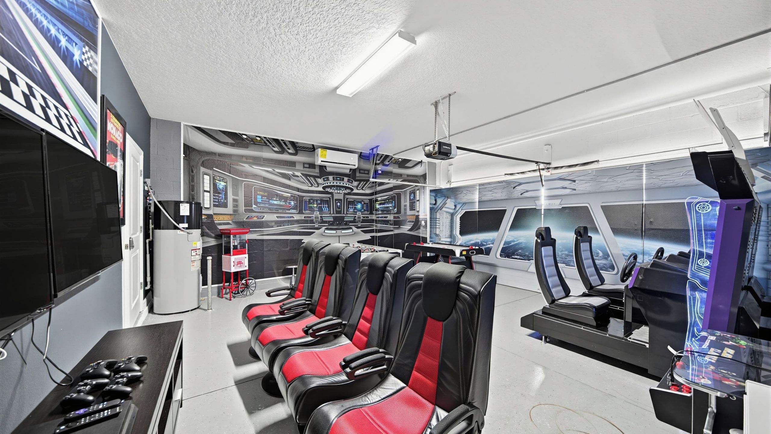Una sala de control con múltiples monitores, una pantalla grande mostrando una escena espacial y varias sillas de juego.