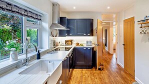 Une cuisine moderne avec une fenêtre, un évier, une cuisinière et des meubles de rangement de couleur sombre.