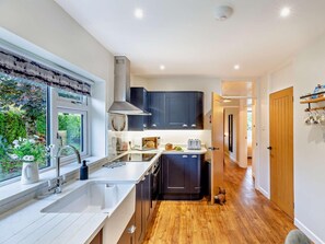 A modern kitchen with a window, sink, stove, and dark cabinets. - 3 Bed in Rhayader (oc-90282) (Saint Harmon)