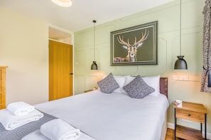 A neatly made bed with patterned pillows, a framed deer head artwork above it, and a bedside table with a lamp. - 3 Bed in Rhayader (oc-90282) (Saint Harmon)