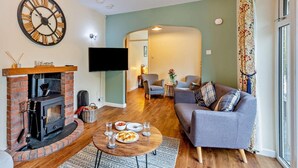 Un salon avec une cheminée, un téléviseur à écran plat, un canapé et une table à manger.