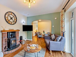 A living room with a fireplace, a flat-screen TV, a sofa, and a dining table. - 3 Bed in Rhayader (oc-90282) (Saint Harmon)