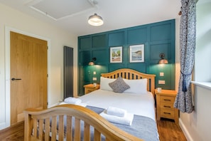 A neatly made bed with a wooden headboard, a bedside table with a lamp, and a wall with framed pictures. - 3 Bed in Rhayader (oc-90282) (Saint Harmon)