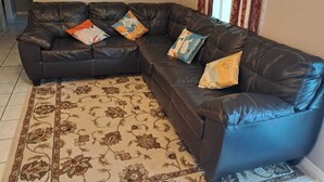 Ein modulares Sofa mit mehreren Kissen, ein gemustertes Teppich und ein gerahmtes Kunstwerk an der Wand.