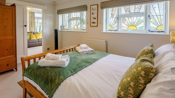 Um quarto com uma cama, um guarda-roupa de madeira, um radiador e uma janela com vista.