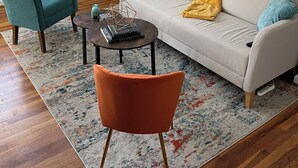 Ein Wohnzimmer mit einer Couch, zwei Sesseln, einem Couchtisch, einer Lampe und Bildern an der Wand.