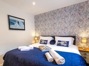 Ein Hotelzimmer mit einem Bett, einem gerahmten Bild an der Wand und blumigem Wandpapier.