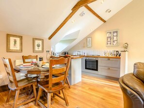A dining area with a wooden table and chairs, a kitchen with modern appliances, and a loft-style ceiling.