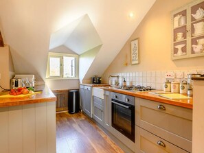 Une cuisine avec un plan de travail en bois, une fenêtre, un évier, une cuisinière et des placards.