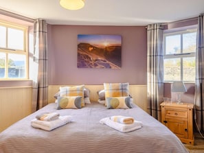 Une chambre à coucher avec un lit, des oreillers, une table de chevet, une lampe et un tableau au mur.