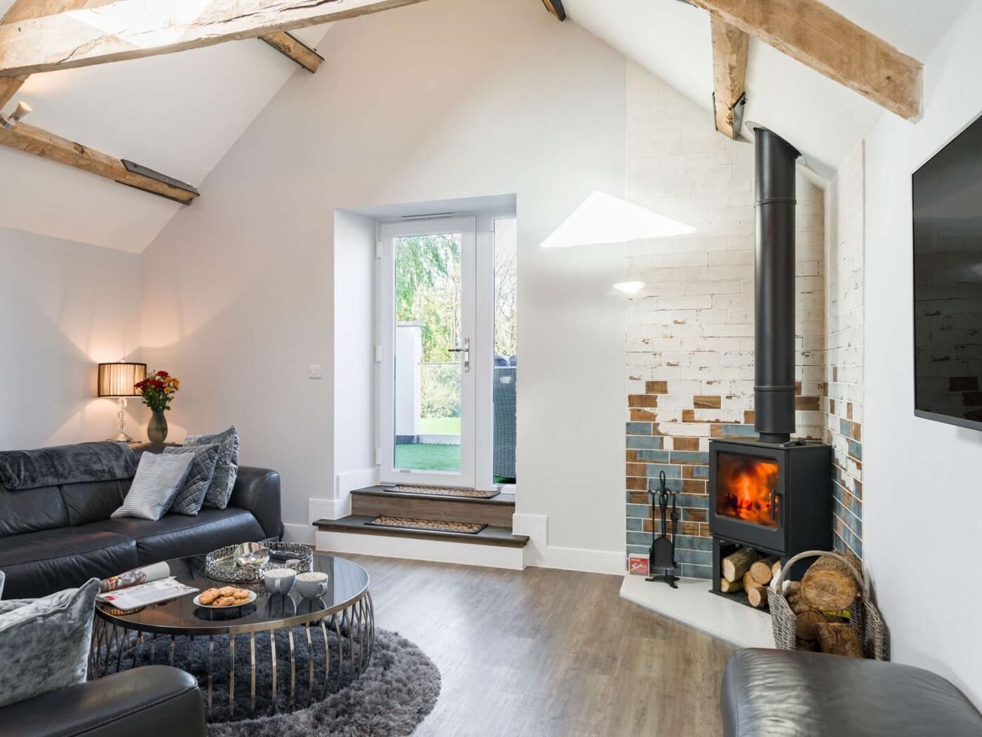 Una sala de estar moderna con chimenea, un sofá, una mesa de centro y vistas al exterior.