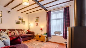 Ein gemütliches Wohnzimmer mit einer Couch, einer Holzkommode, einem Fenster mit Vorhängen und einem Kamin.