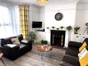 Ein Wohnzimmer mit Kamin, Fernseher und einer Couch.