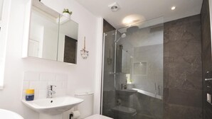 Une salle de bain moderne avec une douche à parois de verre, un lavabo blanc et des toilettes.