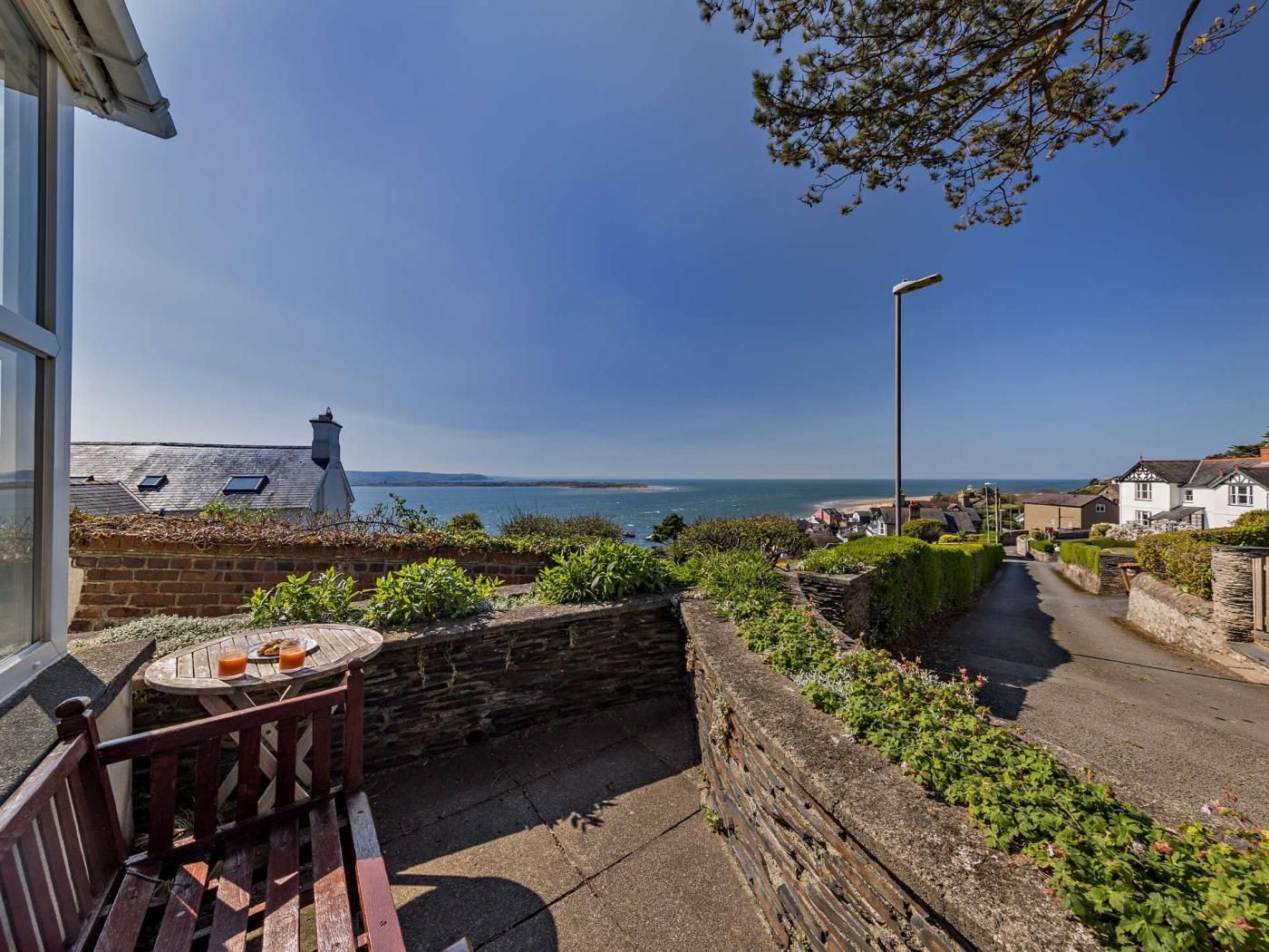 Une vue sur la mer avec un banc et une table, un mur de pierre et une rue menant à la plage.