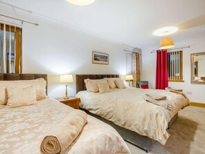 A hotel room with two beds, a nightstand with a lamp, a window with curtains, a wall-mounted mirror, and a ceiling light. - 3 Bed in Bathgate (oc-90491) (Fauldhouse)