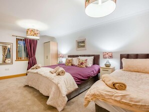 Ein Hotelzimmer mit zwei Betten, einem Schrank, einem Nachttisch, einer Lampe und einem Bild an der Wand.