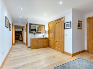 A hallway with wooden flooring, a wooden cabinet, a mirror, and a door. - 3 Bed in Bathgate (oc-90491) (Fauldhouse)