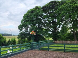 Ein eingezäunter Bereich mit einem großen Baum und einer Blumendekoration an einem Pfosten.