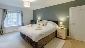 A bedroom with a bed, bedside tables, a window with curtains, and a door. - 4 Bed in Hexham (oc-90521) (Bardon Mill)