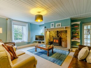 A cozy living room with a fireplace, a sofa, a television, and a bookshelf. - 4 Bed in Hexham (oc-90521) (Bardon Mill)