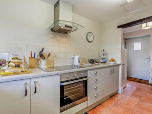 Een keuken met een roestvrijstalen oven, een koffiezetapparaat en een klok aan de muur.