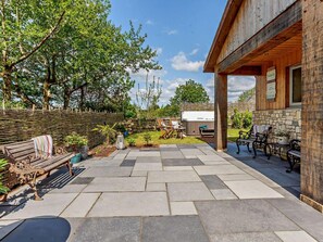 Eine Terrasse mit Steinboden, Sitzgelegenheiten im Freien und einem Holzzaun.