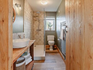 Ein Badezimmer mit einem großen Waschbecken, Toilette, Dusche und einem Holzkosmetikschrank.